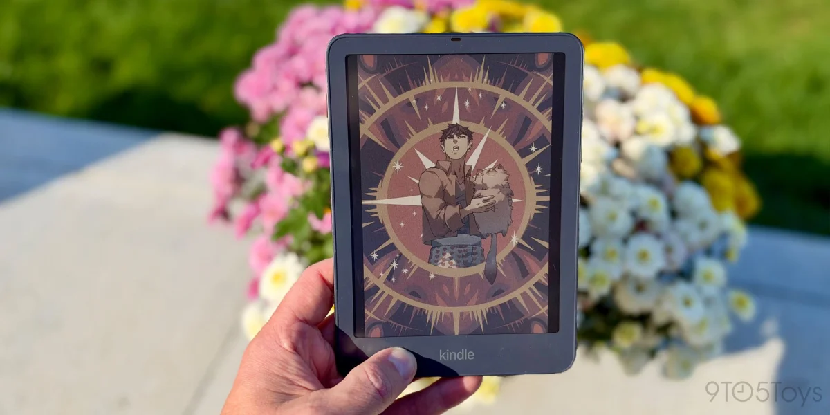 A hand holding a tablet with a cartoon on the screen