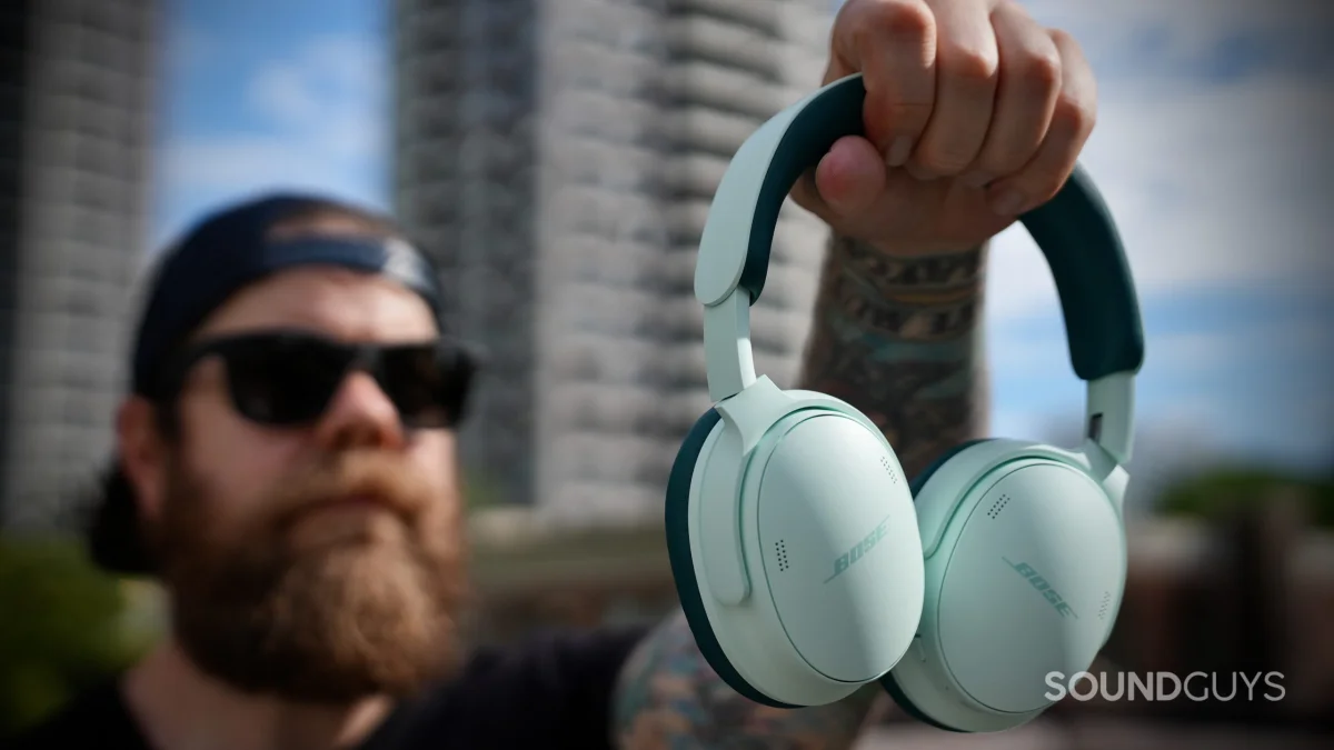 The Bose QuietComfort Headphones (2nd Gen) in green held up outdoors.