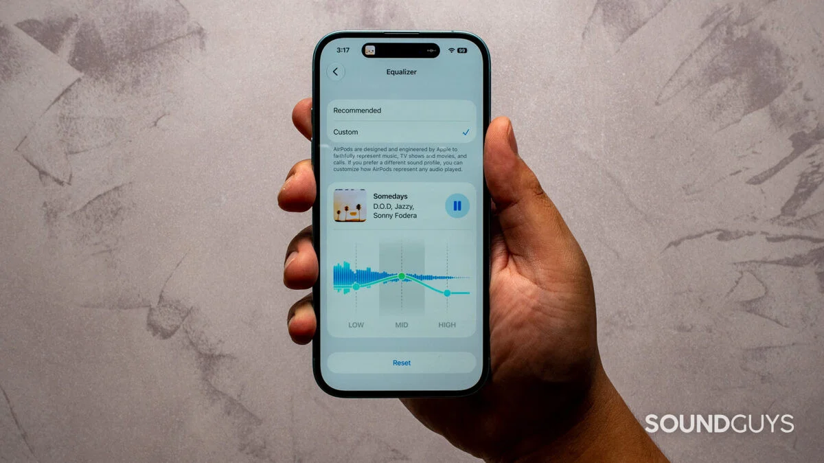 A hald holding an iphone showing the airpods custom equalizer settings