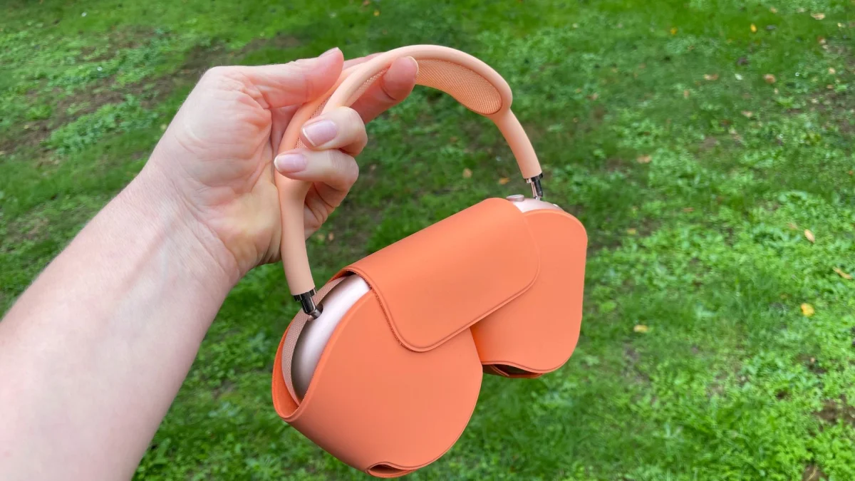 Apple AirPods Max 2, held in front of a garden lawn